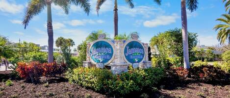 A sign with 'Jamaica Royale' and the number '5830' surrounded by palm trees and shrubs.