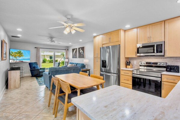 A modern kitchen with wooden cabinets, stainless steel appliances, and a dining area with a table and chairs. - Jamaica Royale 069 Close to the pool! (Siesta Key)