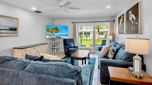 A modern living room with a sofa, armchair, TV, and a ceiling fan. - Jamaica Royale 069 Close to the pool! (Siesta Key)
