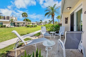 A hotel patio with outdoor seating, palm trees, and a clear sky. - Jamaica Royale 069 Close to the pool! (Siesta Key)