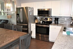 Enjoy cooking in this well-equipped kitchen with a refrigerator, microwave, and oven, and dine at the adjacent table.