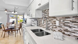 Una cocina moderna con gabinetes blancos, un lavamanos doble y una salpicadera de azulejos.