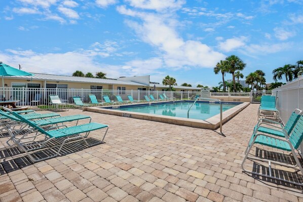 A swimming pool area with lounge chairs and a fenced poolside.