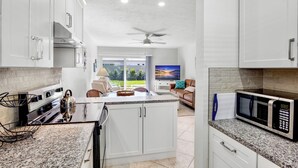 A modern kitchen with white cabinets, granite countertops, and a built-in microwave. - Jamaica Royale 079 Updated and closest to the beach! (Siesta Key)