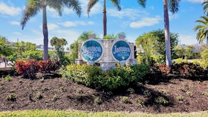 A sign with 'Jamaica Royale' and the number '5830' surrounded by palm trees and shrubs.