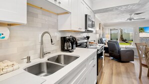 Una cocina moderna con electrodomésticos de acero inoxidable, un lavamanos doble y una zona de comedor con vistas.