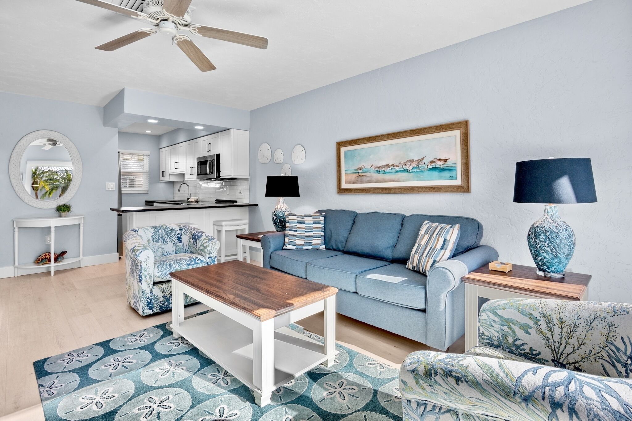 Een moderne woonkamer met een blauwe bank, een houten salontafel en vloerkleden met een patroon.
