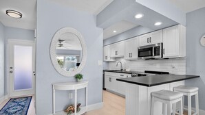 A modern kitchen with white cabinets, a black countertop, and a round mirror. - Jamaica Royale 083 Updated and close to the beach! (Siesta Key)
