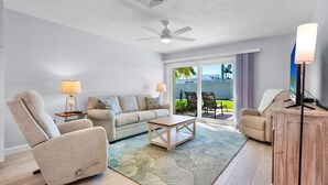 A living room with a sofa, armchair, coffee table, and a TV stand. - Jamaica Royale 086 Updated and close to the beach! (Siesta Key)