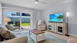 A living room with a sofa, coffee table, TV, and a cabinet. - Jamaica Royale 086 Updated and close to the beach! (Siesta Key)