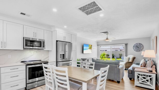 A modern kitchen with white cabinets, a microwave, and a refrigerator. - Jamaica Royale 090 Nicely updated! (Siesta Key)