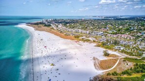 An aerial view of a coastal area with a beach, buildings, and a marina. - Jamaica Royale 090 Nicely updated! (Siesta Key)