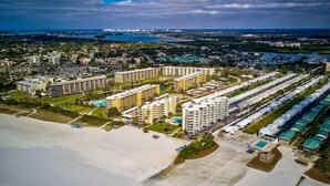 A coastal resort with multiple high-rise buildings, a beach area, and a marina in the background. - Jamaica Royale 090 Nicely updated! (Siesta Key)