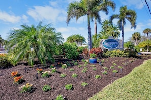 A landscaped area with a sign for 'Jamaica Royale,' surrounded by palm trees and various plants.
