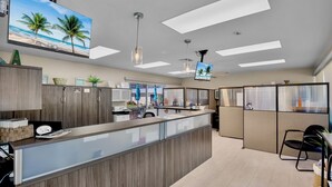 A modern hotel lobby with a reception desk, seating area, and a large TV screen displaying a beach scene. - Jamaica Royale 099 Nice Gulf side unit! (Siesta Key)