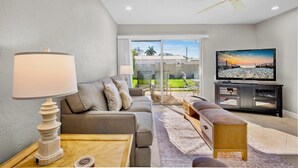 Ein modernes Wohnzimmer mit einer Couch, einem Couchtisch, einem Fernseher und einem Deckenventilator.