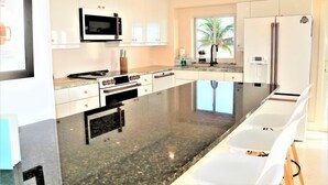 Een moderne keuken met witte kastjes, een granieten aanrecht, een ingebouwde oven, een magnetron en een koelkast.