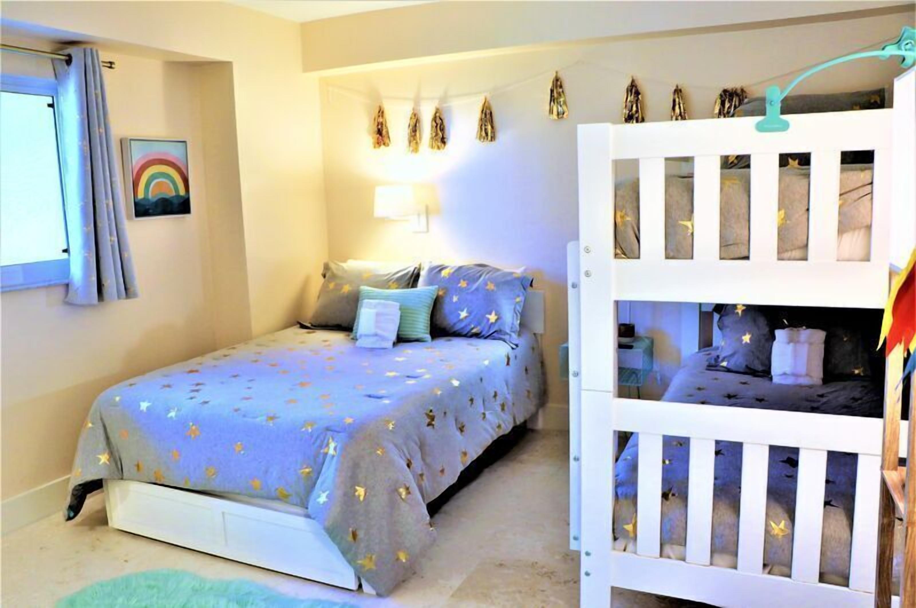 Un dormitorio con una cama, una mesita de noche, una lámpara y una cuna.