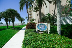 Welcome to our hotel, where a clear pathway leads to a modern building with balconies and beautifully maintained surroundings.