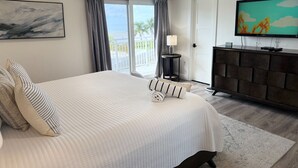 Une chambre avec un grand lit, une télévision, une commode et une vue sur l’extérieur.