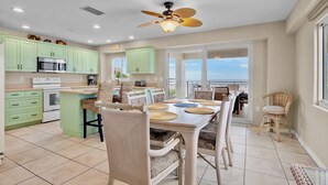Une cuisine spacieuse avec des meubles de couleur verte, un coin repas avec une table et des chaises, et un balcon avec vue.