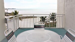 Un balcón con vista a la playa, una mesa redonda y dos sillas.