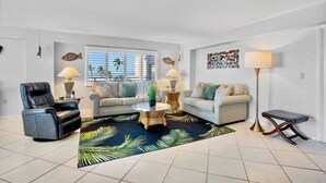 A living room with a sofa, armchair, coffee table, and floor lamp.