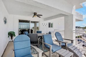 A balcony with outdoor furniture, a ceiling fan, and a view of the surrounding area. - Book Your Coastal Escape at Jamaica Royale 405: Beachfront Condo with Balcony (Siesta Key)