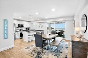 A modern kitchen with white cabinets, a central island, and a dining area with a table and chairs.