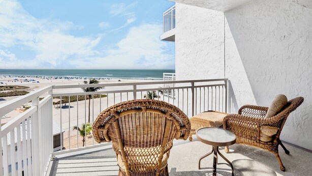 Een balkon met rieten meubilair en uitzicht op het strand.