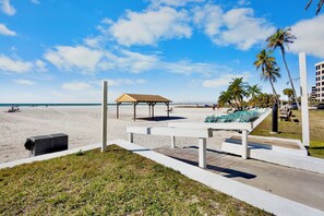 Une vue sur la plage avec une terrasse en bois, des chaises longues et un espace salon abrité.