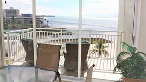 A balcony with wicker chairs and a table, overlooking a beach and cityscape. - Jamaica Royale 603 Nicely updated and Great views! (Siesta Key)