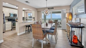 A spacious kitchen with modern appliances, a dining area with wicker chairs, and a view of the ocean. - Jamaica Royale 604 Beautfully updated and great views! (Siesta Key)