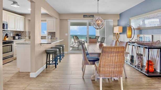 A spacious kitchen with modern appliances, a dining area with wicker furniture, and a view to the outside. - Jamaica Royale 604 Beautfully updated and great views! (Siesta Key)
