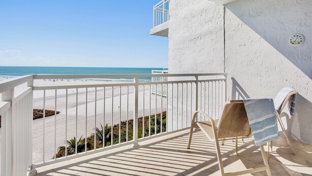 A balcony with a view of the beach, a white railing, and two wicker chairs with striped towels. - Experience the Best of Siesta Key at Jamaica Royale 702 with Gulf Views! (Siesta Key)