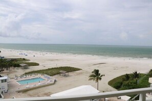 A beach view from a balcony with a pool and lounge chairs. - Unforgettable Friends Getaway Awaits at Beachfront Siesta Key Condo! (Siesta Key)