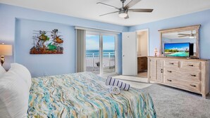 A bedroom with a bed, a ceiling fan, a TV, a painting, and a view of the ocean. - Family Beach Getaway at Jamaica Royale 705 in Siesta Key! (Siesta Key)