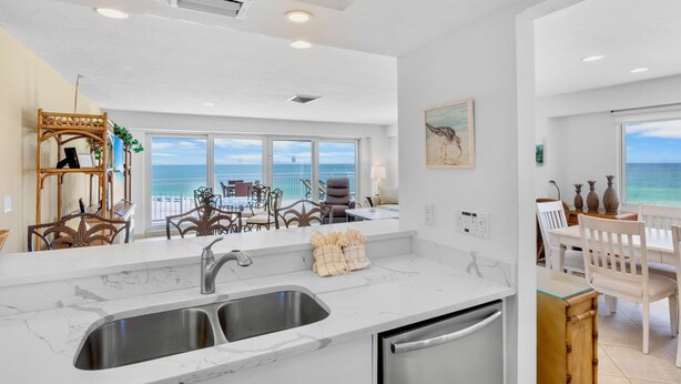 A modern kitchen with a large island, double sink, and a view of the ocean. - Couples Beachfront Getaway at Jamaica Royale 801 in Siesta Key! (Siesta Key)