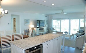 A spacious kitchen with a central island, white cabinetry, and a dining area with chairs.