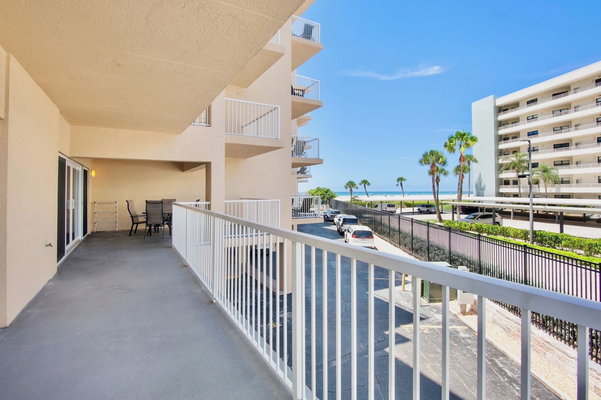 A balcony with a view of the beach and a parking area.