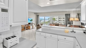 A modern kitchen with a central island, a dining area with a view, and a living space with a large window overlooking the ocean. - Jamaica Royale T43 Nice updates and Great views! (Siesta Key)