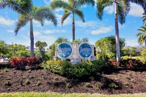 A sign with 'Jamaica Royale' and the number '5830' surrounded by palm trees and shrubs.