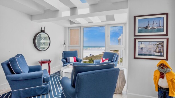 A room with a large window, a round wall clock, and two framed pictures on the wall.
