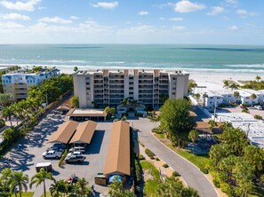 A beachfront hotel with multiple floors, a parking area, and a view of the ocean.