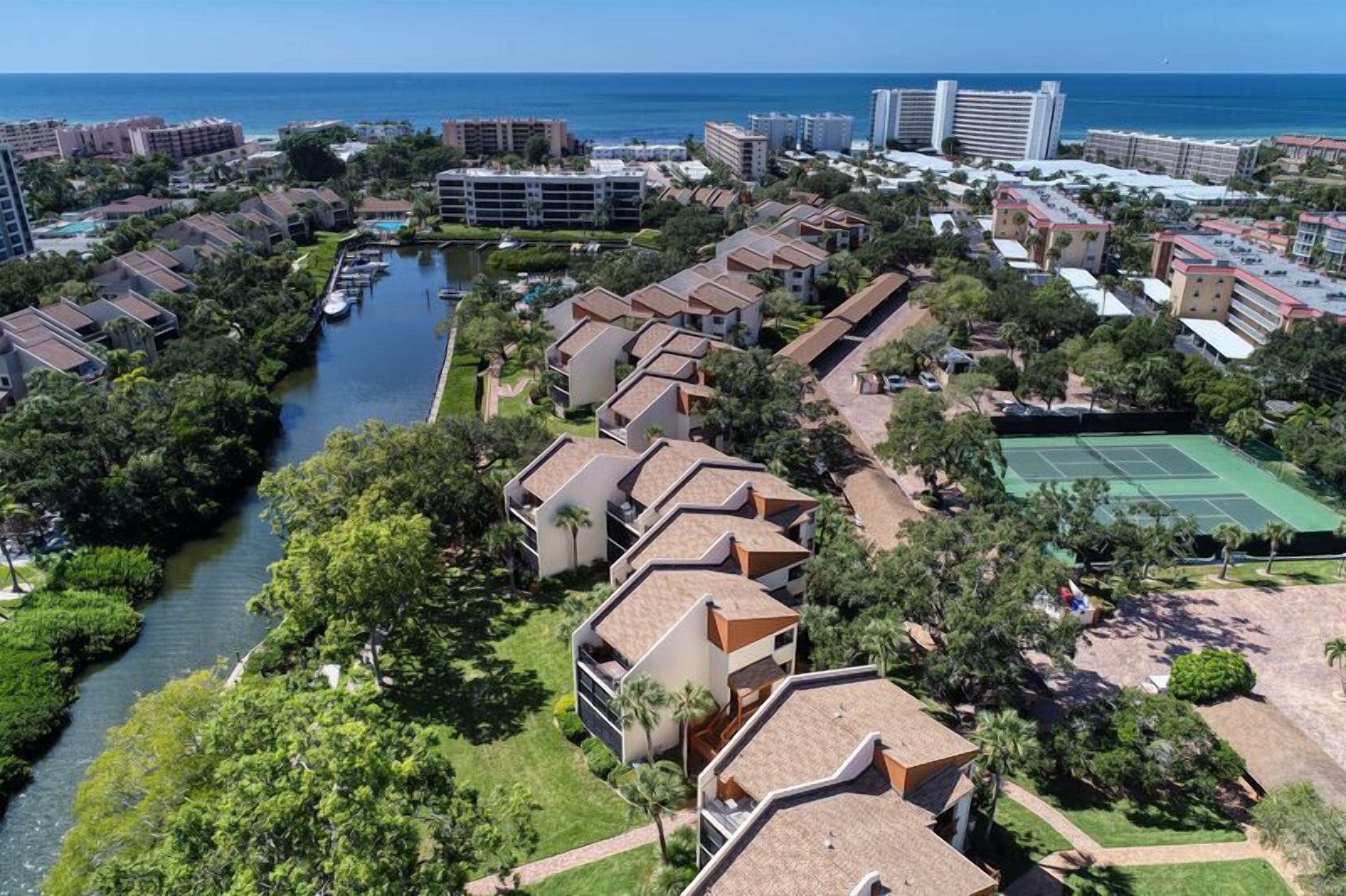 A coastal resort with multiple-story buildings, a marina, and a tennis court.