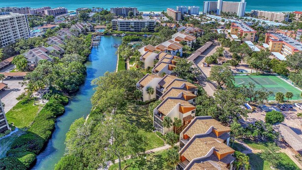 An aerial view of a coastal resort with multiple buildings, a river, and a tennis court. - Midnight Cove II 313F: Siesta Key Condo with Beach, Pool, Pickleball Access (Siesta Key)