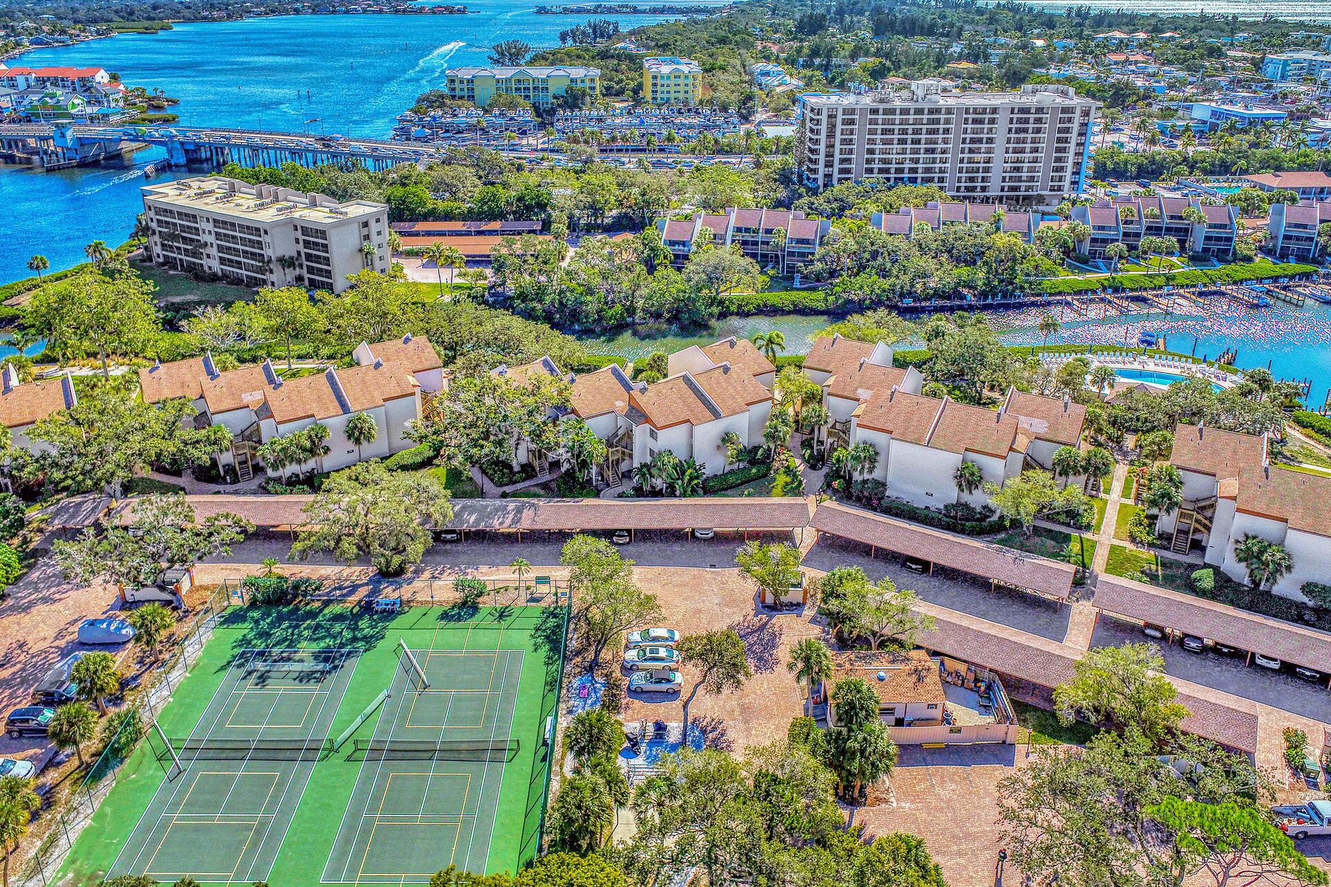An aerial view of a coastal resort with multiple buildings, a marina, and a large beach area.