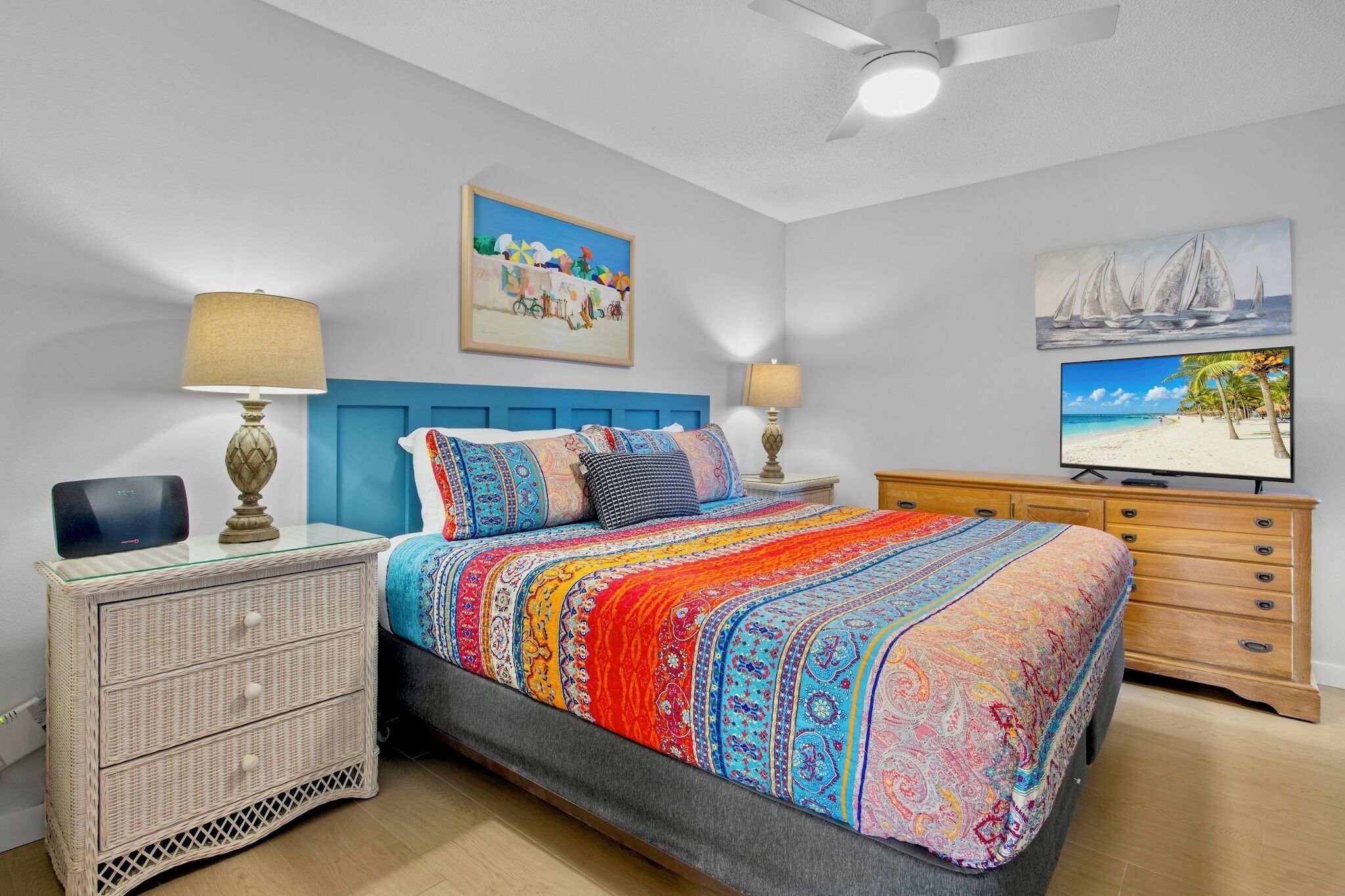 A bedroom with a bed, bedside tables, a dresser, and artwork on the walls.