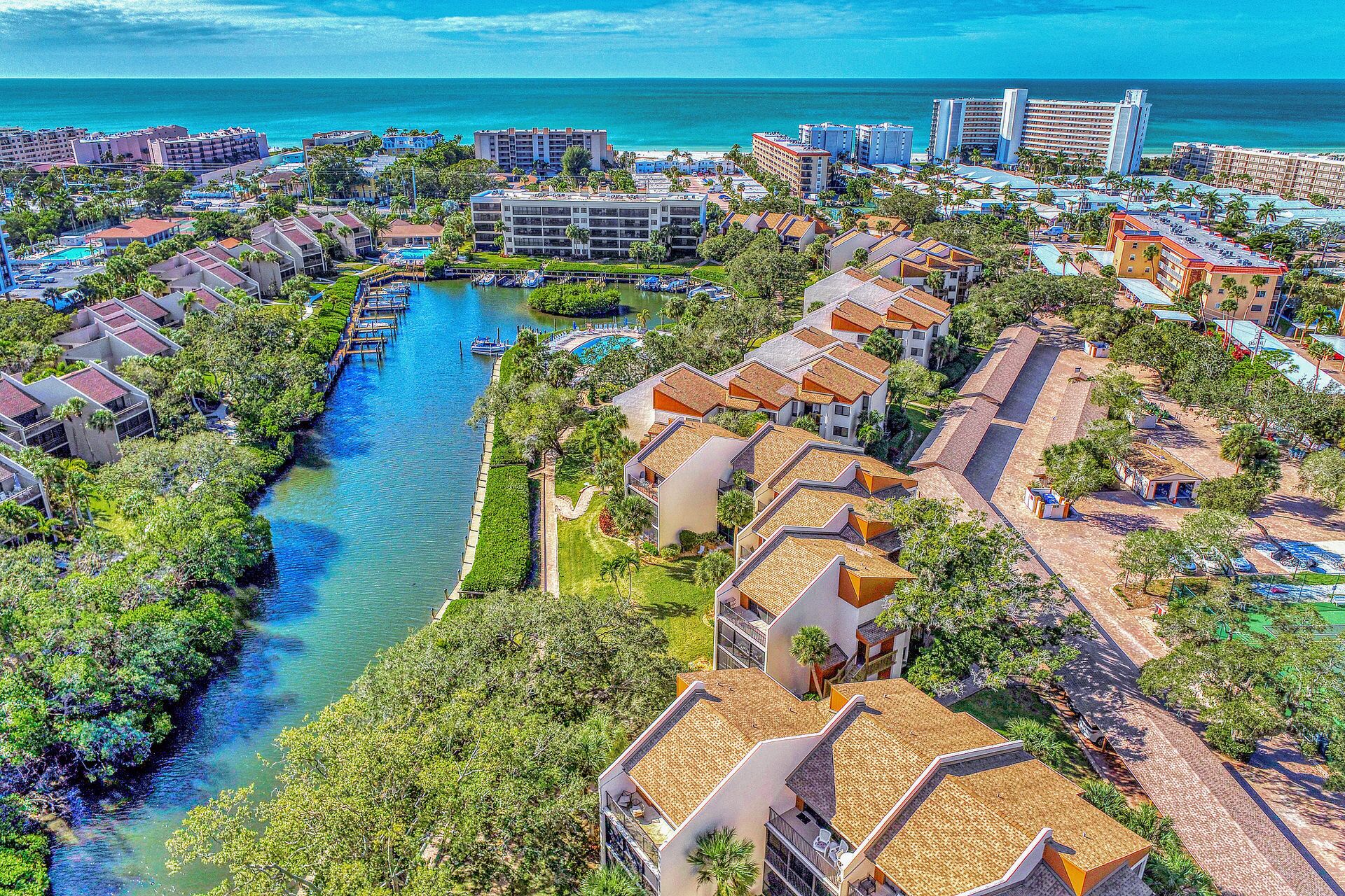 An aerial view of a coastal resort with multiple buildings, a marina, and a river.