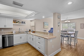A modern kitchen with white cabinetry, a stainless steel dishwasher, and a granite countertop. - Midnight Cove II 420D - Stunning Siesta Key Condo with Lanai (Siesta Key)
